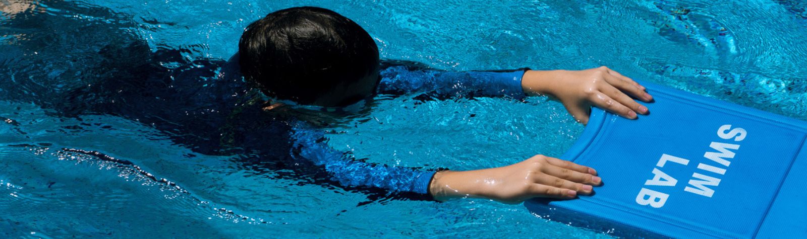 A Young Child Learning to Swim with a Kickboard at The Swim Lab